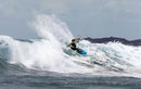 Rider a surfar uma onda com o kite Duotone Dice SLS 2025 junto a um cabo rochoso