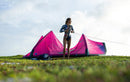 Rider de pé junto ao kite Duotone Dice SLS 2026 cor-de-rosa, na relva