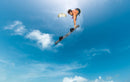 Rider a fazer um salto de big air com twintip e fixações Duotone Entity Ergo 2026 sob um céu azul