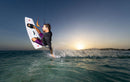 Rider aterrizando al atardecer con una twintip Select y fijaciones Duotone Entity Ergo 2027