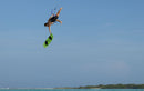 Rider haciendo un aéreo con twintip verde lima y fijaciones Duotone Entity Ergo 2027 sobre agua turquesa
