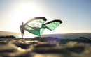 Rider com o kite Duotone Evo 2026 numa praia rochosa em contraluz