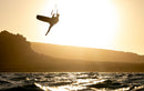 Rider a fazer um salto com o Duotone Evo 2026 ao pôr do sol em frente a uma costa rochosa