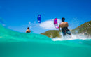 Rider a navegar com o Duotone Evo SLS 2025 numa praia tropical com colinas verdes
