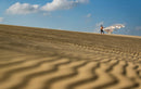 Rider com o kite Duotone Evo SLS 2026 sobre dunas de areia junto à praia