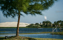 Rider a navegar com o Duotone Evo SLS 2026 numa lagoa tropical com dunas e palmeiras