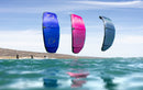Kites Duotone Juice 2026 azul e rosa a voar rente à água junto a outros riders
