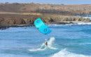 Duotone Neo D/LAB 2026 turchese sopra un rider che surfa vicino alla costa rocciosa