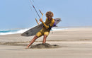 Rider che cammina sulla spiaggia con la tavola da surf e la barra del Duotone Neo D/LAB 2026