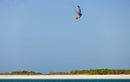 Rider che salta alto con il kite Duotone Rebel D/LAB 2025 su una spiaggia tropicale dall'acqua turchese