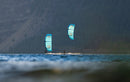 Riders with Duotone Rebel D/LAB 2026 kites on a mountain lake with wooded slopes