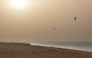 Rider a saltar sobre uma praia de areia com neblina de poeira e o kite Duotone Rebel SLS 2026