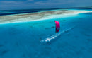 Vista aérea de um rider a navegar com o kite Duotone Rebel SLS 2027 magenta sobre uma lagoa turquesa