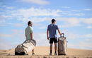 Dos riders con la Duotone Team Bag 2027 marfil y una maleta en las dunas