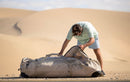 Rider abriendo la Duotone Team Bag 2027 marfil en las dunas del desierto