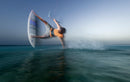 Rider rozando el agua en un truco con tabla de surf Duotone con pads, sesión Traction Pad Front 2027