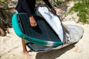 Rider metiendo una tabla de wing en la funda Duotone Wing Boardbag Single 2027 marfil sobre la arena