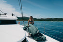 Rider con la funda Duotone Wing Boardbag Single 2027 verde en la cubierta de un catamarán