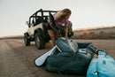 Rider descargando la funda Duotone Wing Boardbag Single 2027 verde de un todoterreno al atardecer
