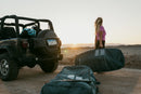 Funda Duotone Wing Boardbag Single 2027 verde en el suelo junto a un todoterreno al atardecer