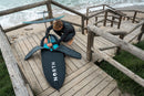 Rider com o North Foil Fullsuit 4/3 mm 2027 a montar o foil num passadiço de madeira
