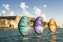 Tre rider con wing North Nova 2026 Turquoise, Deep Purple e Orange in volo sul foil vicino a una fortezza sulla costa