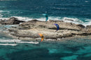 Tres riders navegando con la North Orbit 2026 en Turquoise, Deep Purple y Orange entre rocas y agua turquesa