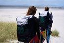 Dos riders caminando por las dunas con la bolsa de la North Reach 2025 a la espalda