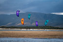 Diversi rider in navigazione con il North Reach 2026 Deep Purple, Orange e Turquoise davanti a una costa montuosa