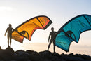 Due rider in controluce con i kite North Reach 2026 Orange e Turquoise al tramonto